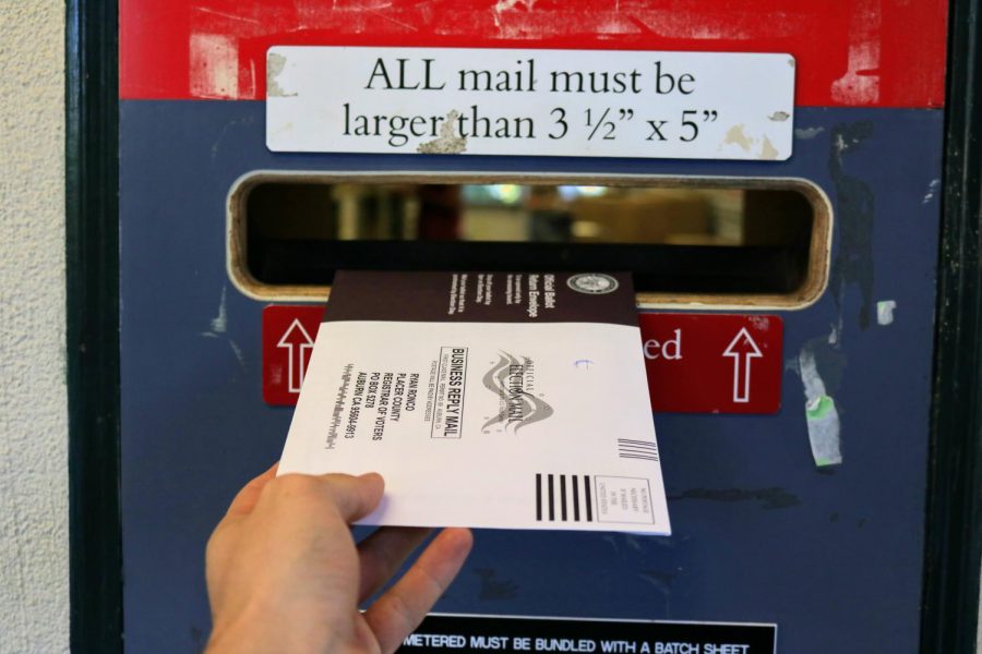 A student submits their ballot in the Mail Centers drop box. 